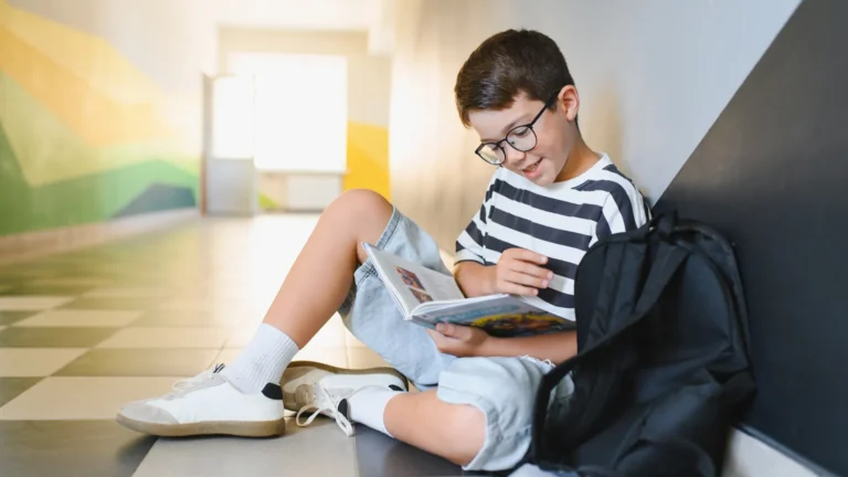 Skolegutt leser i bok på skolen